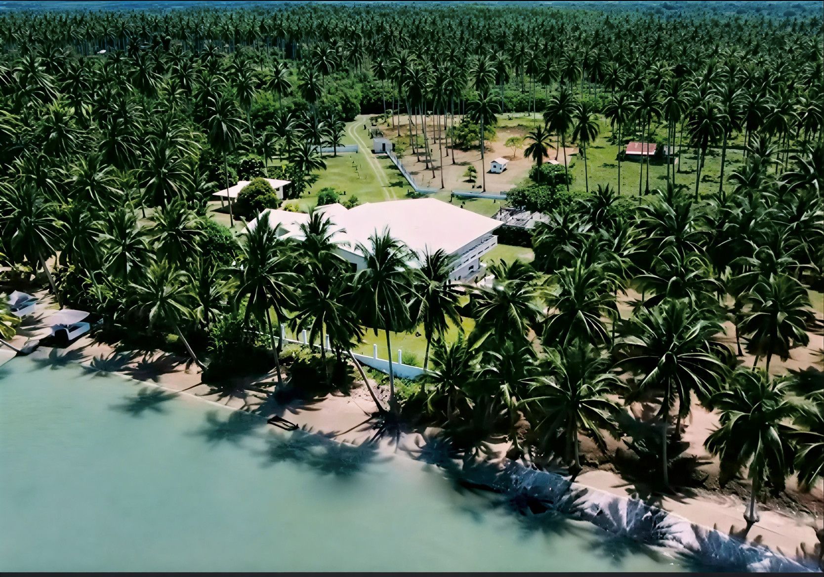 Tropical beachfront property surrounded by palm trees and turquoise water.