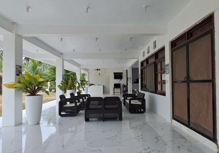 Covered porch with seating; white pillars, shiny floor, potted plants.