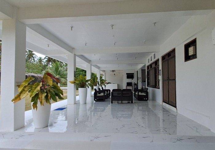 Covered white veranda with potted plants and seating.