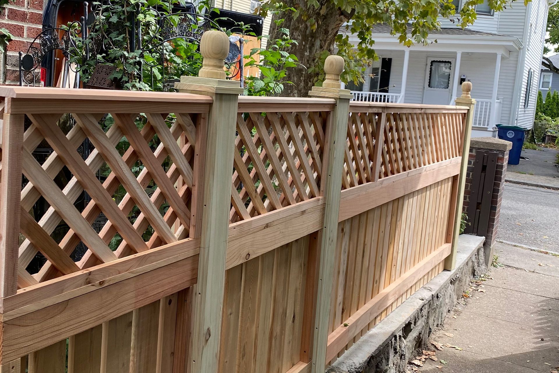 A wooden fence with a lattice design is in front of a house.