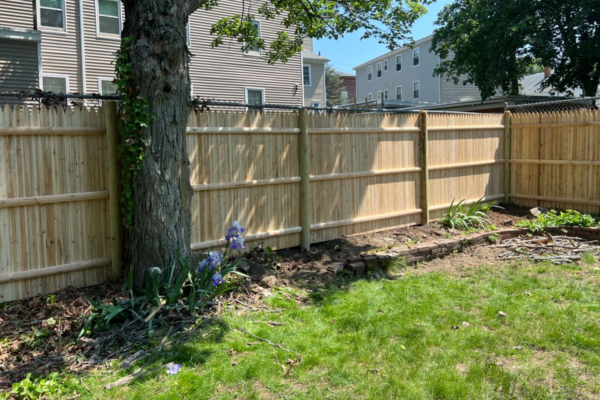 A wooden fence is in the backyard of a house.