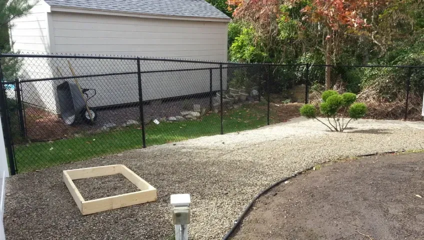 A backyard with a chain link fence and a shed in the background.