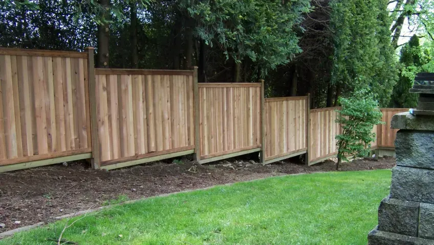 A wooden fence surrounds a lush green yard.