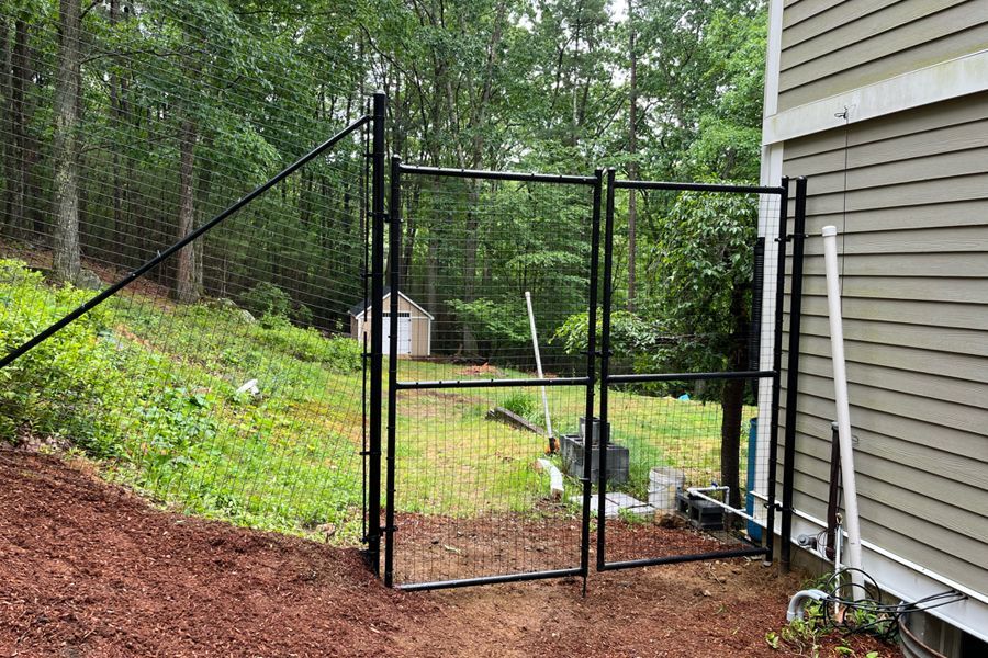 A black fence is surrounding a yard next to a house.