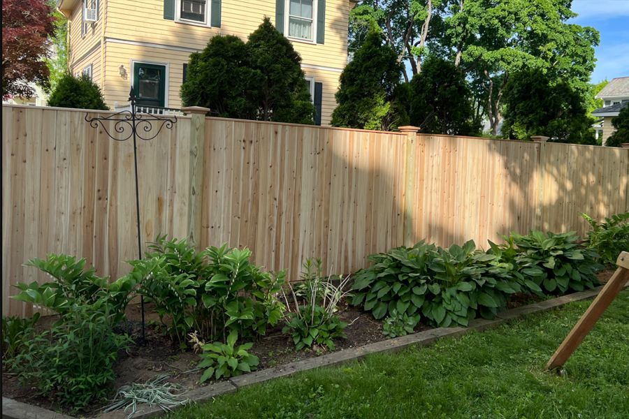 A wooden fence is in the backyard of a house.