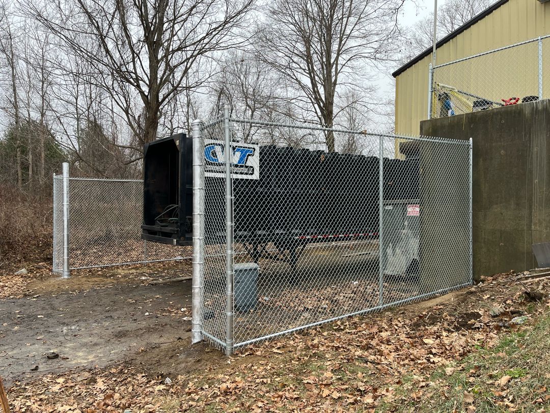 A chain link fence is surrounding a building and a tunnel.