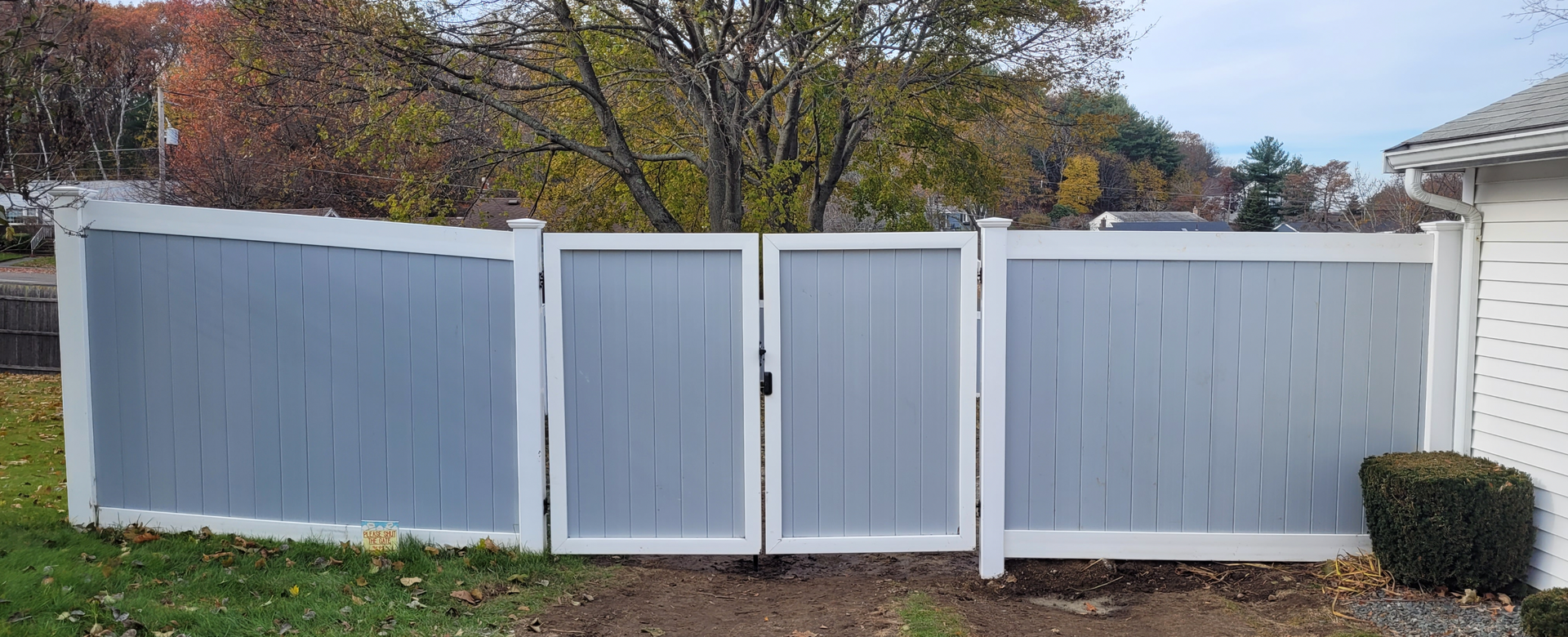 A white fence with a gate in front of a house.
