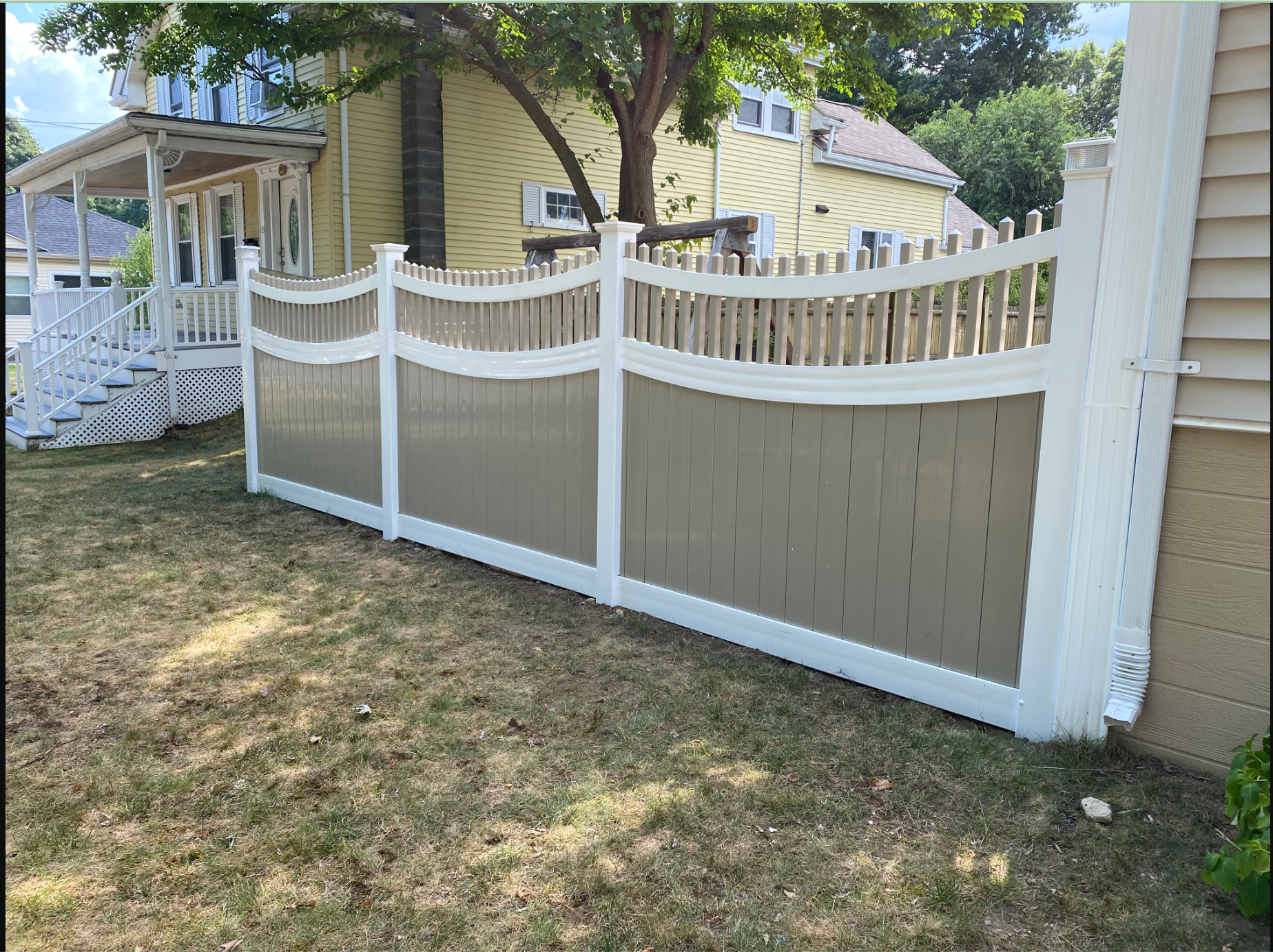 A white and brown fence is in front of a house.