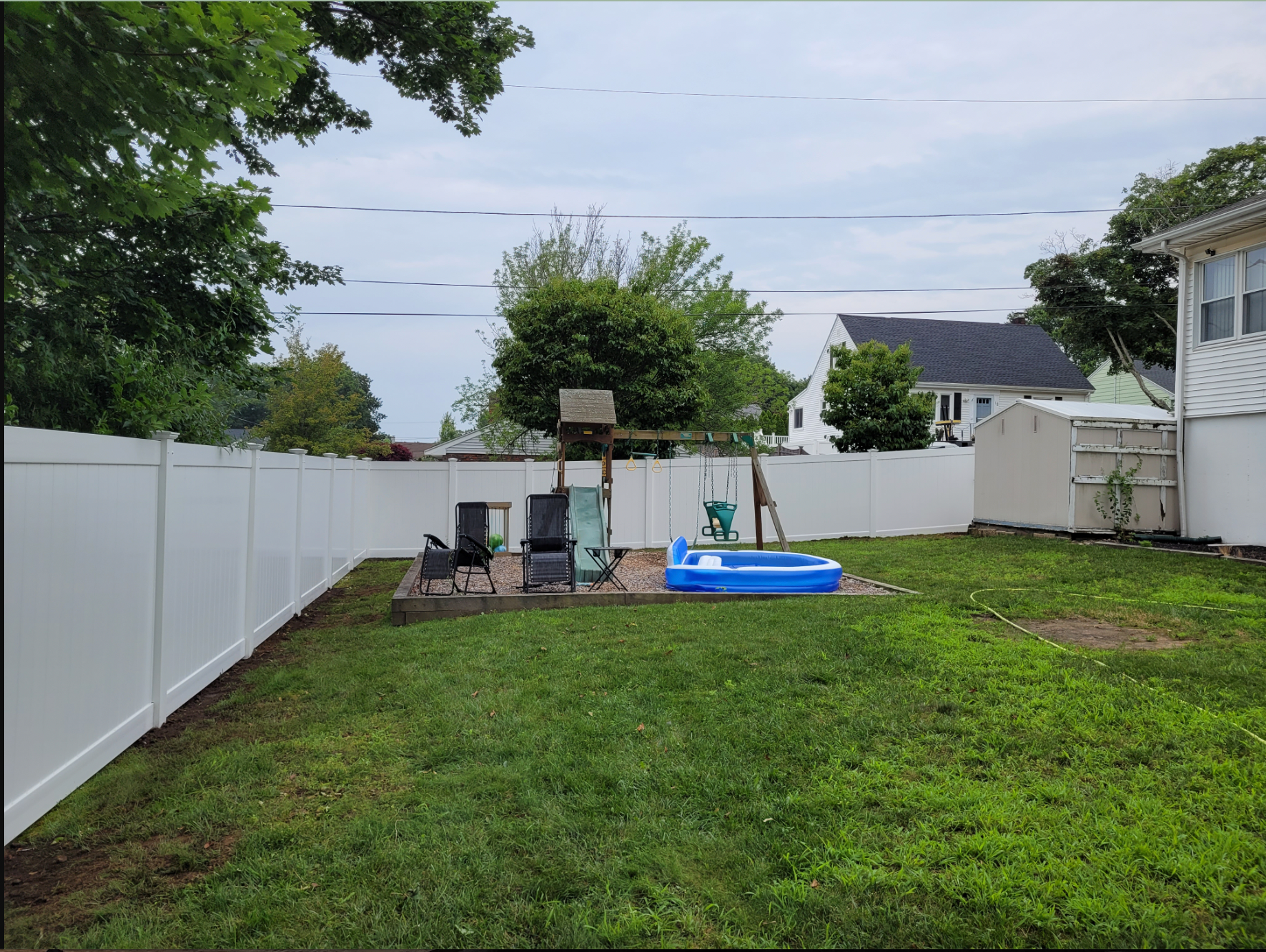 A backyard with a white fence and a blue sandbox