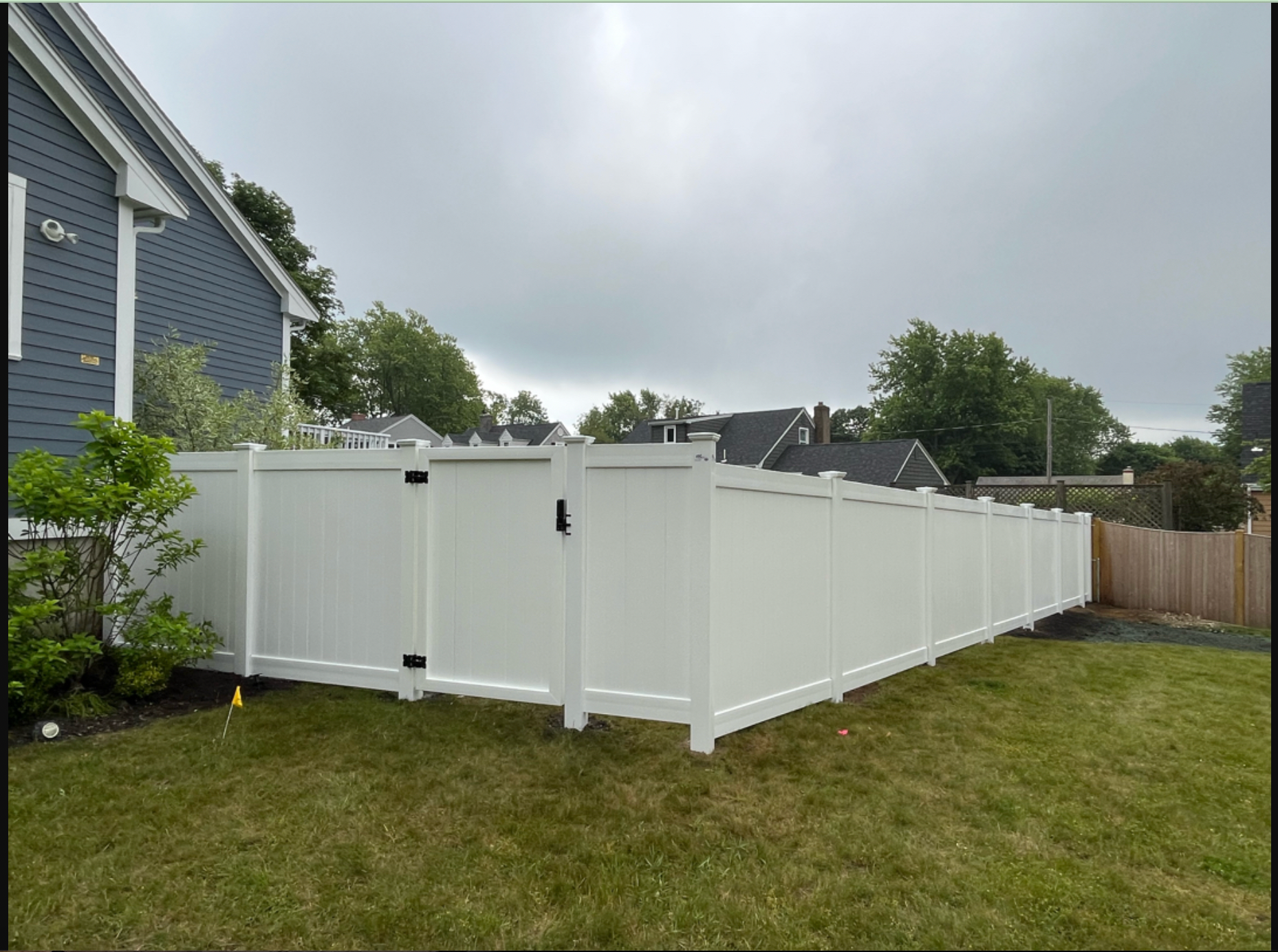 A white fence is in the backyard of a house.
