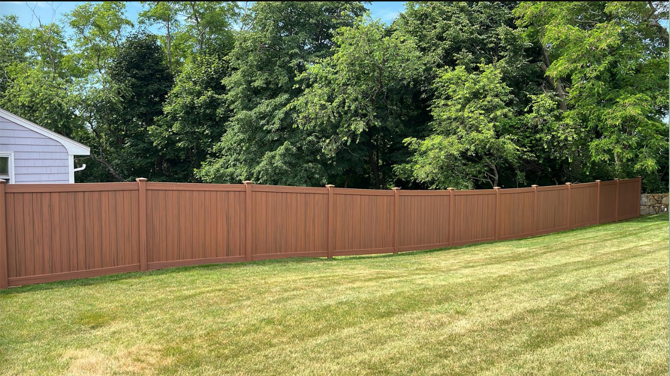A brown wooden fence surrounds a lush green yard.