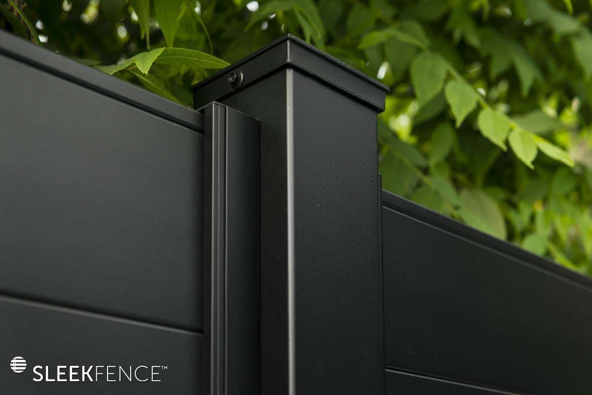 A close up of a black fence with a tree in the background.