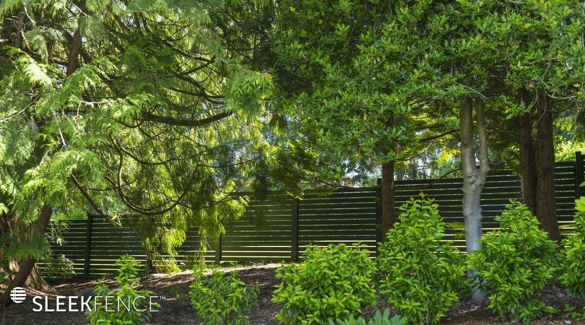 A wooden fence is surrounded by trees and bushes in a garden.
