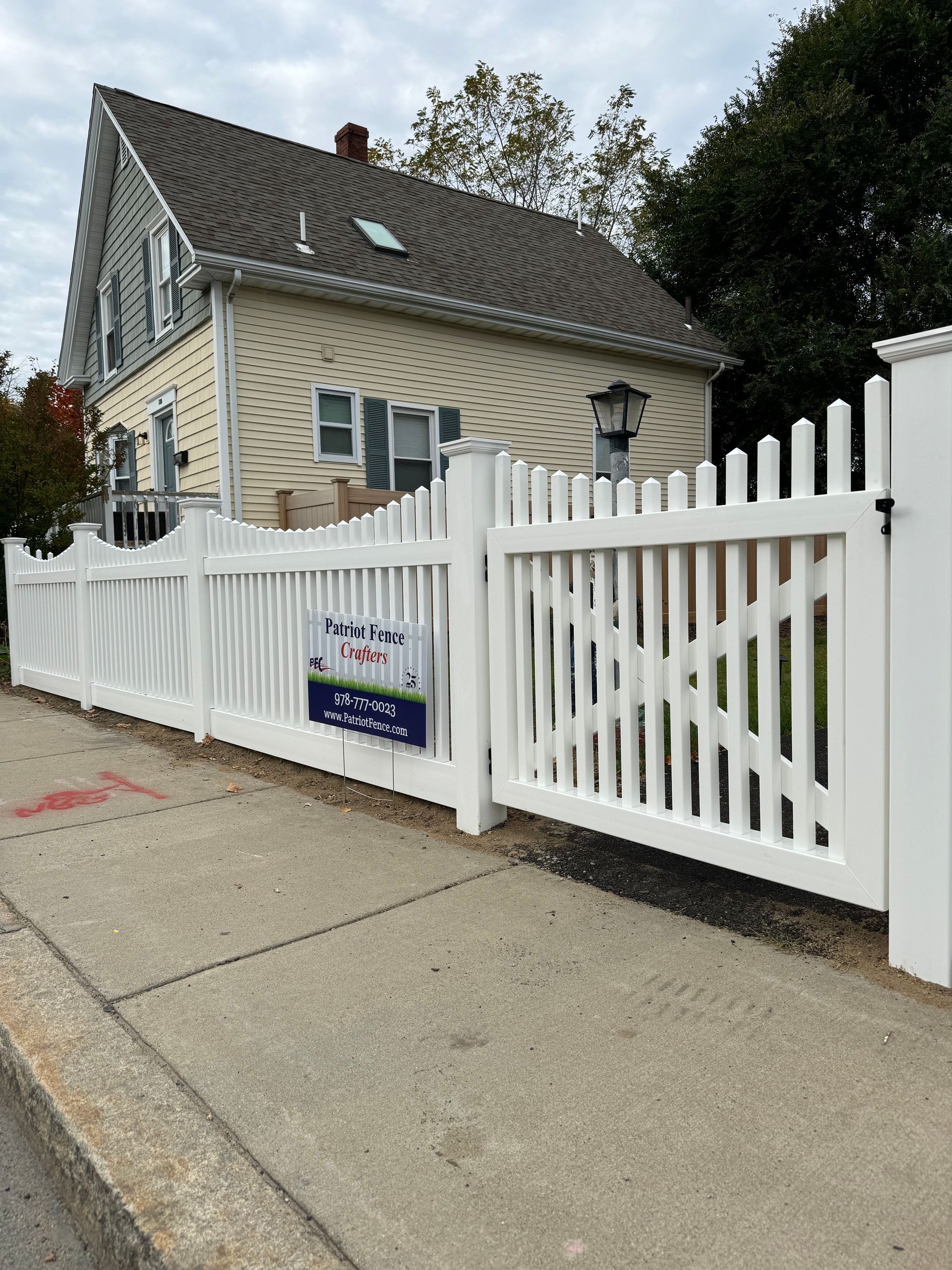 A white picket fence is in front of a house.