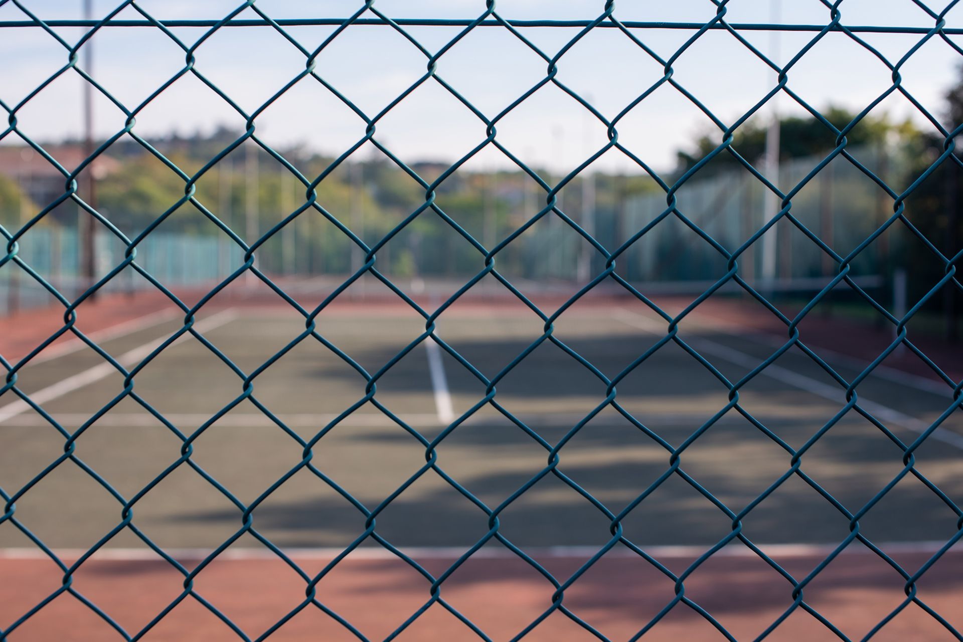 A tennis court is behind a chain link fence.