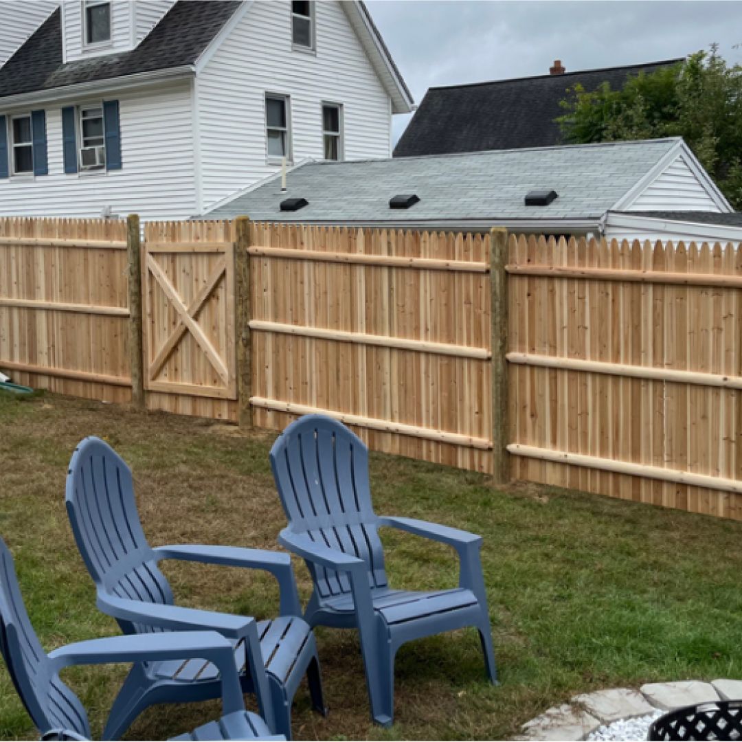 A wooden fence with blue chairs in front of it