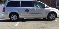 a silver minivan is parked in a parking lot .