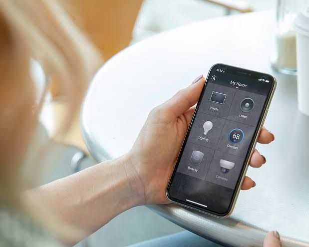 A person is holding a smart phone in their hand while sitting at a table.