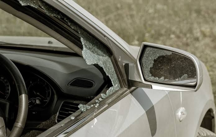 Broken car window and side mirror on a silver vehicle.