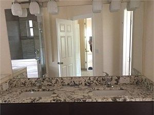 A bathroom with two sinks, two mirrors, and wooden cabinets