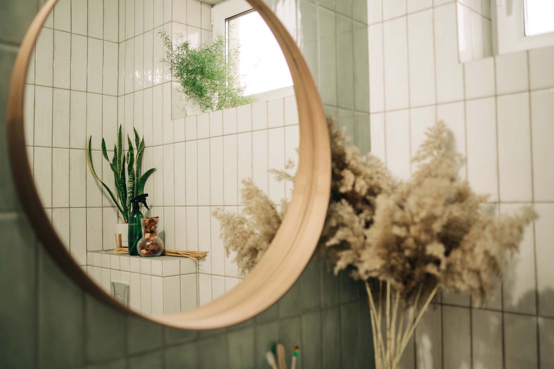 A bathroom with a round mirror and a vase of flowers