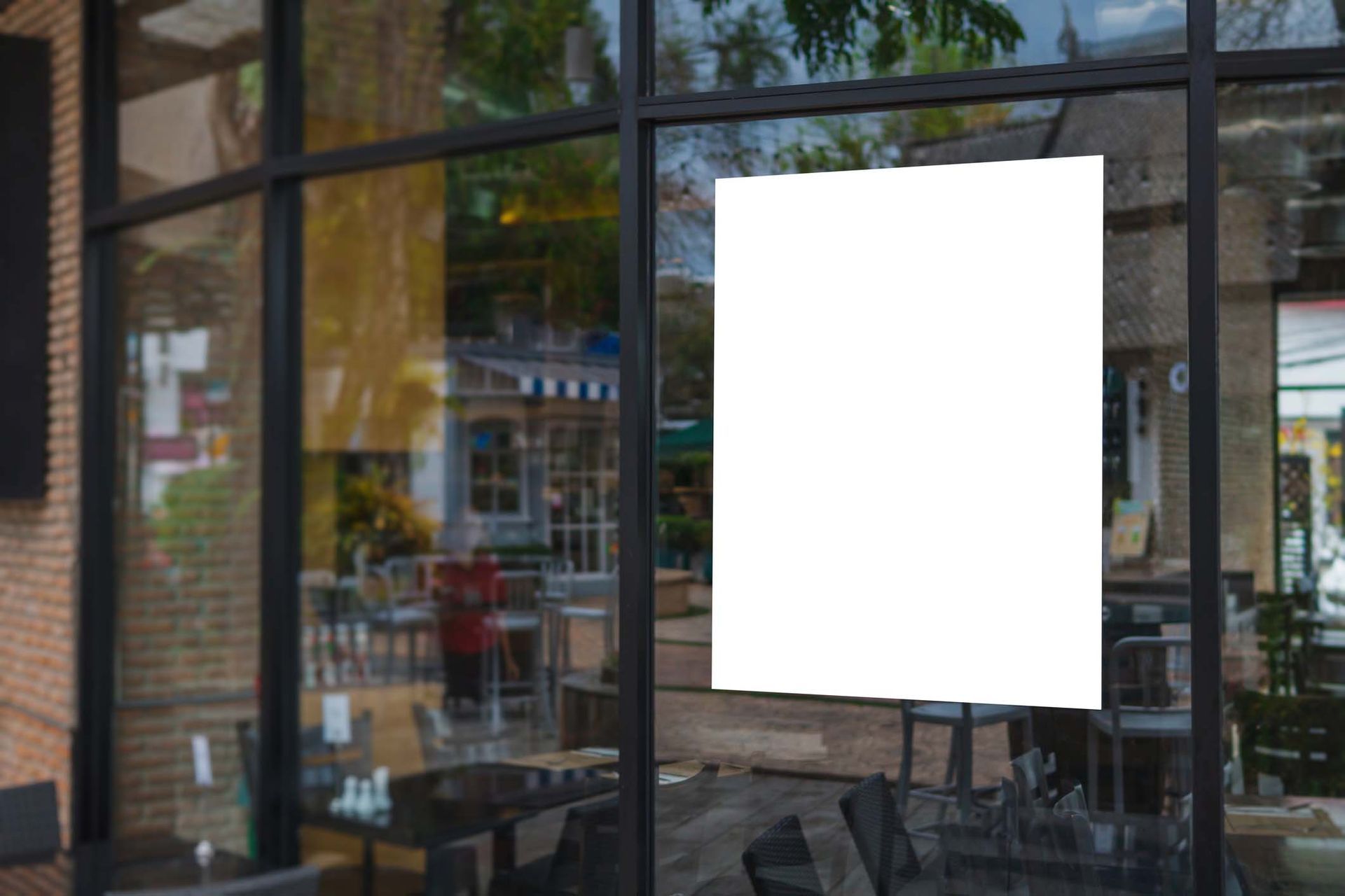 A white poster is hanging on the window of a restaurant