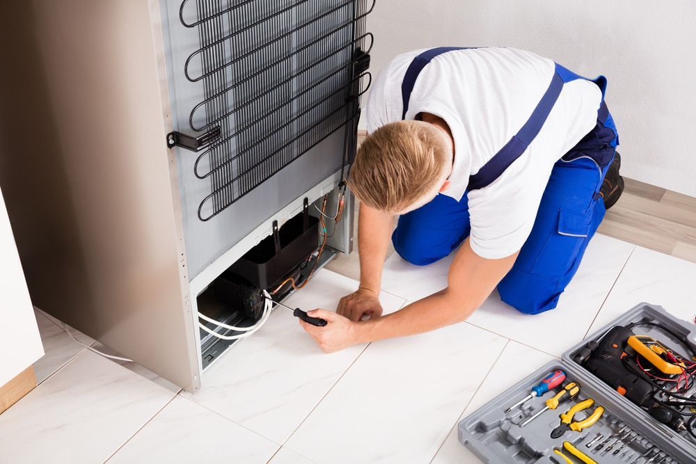 Man Checking The Refrigerator With A Screwdriver — Oriel Refrigeration and Air Conditioning in Warren, NSW
