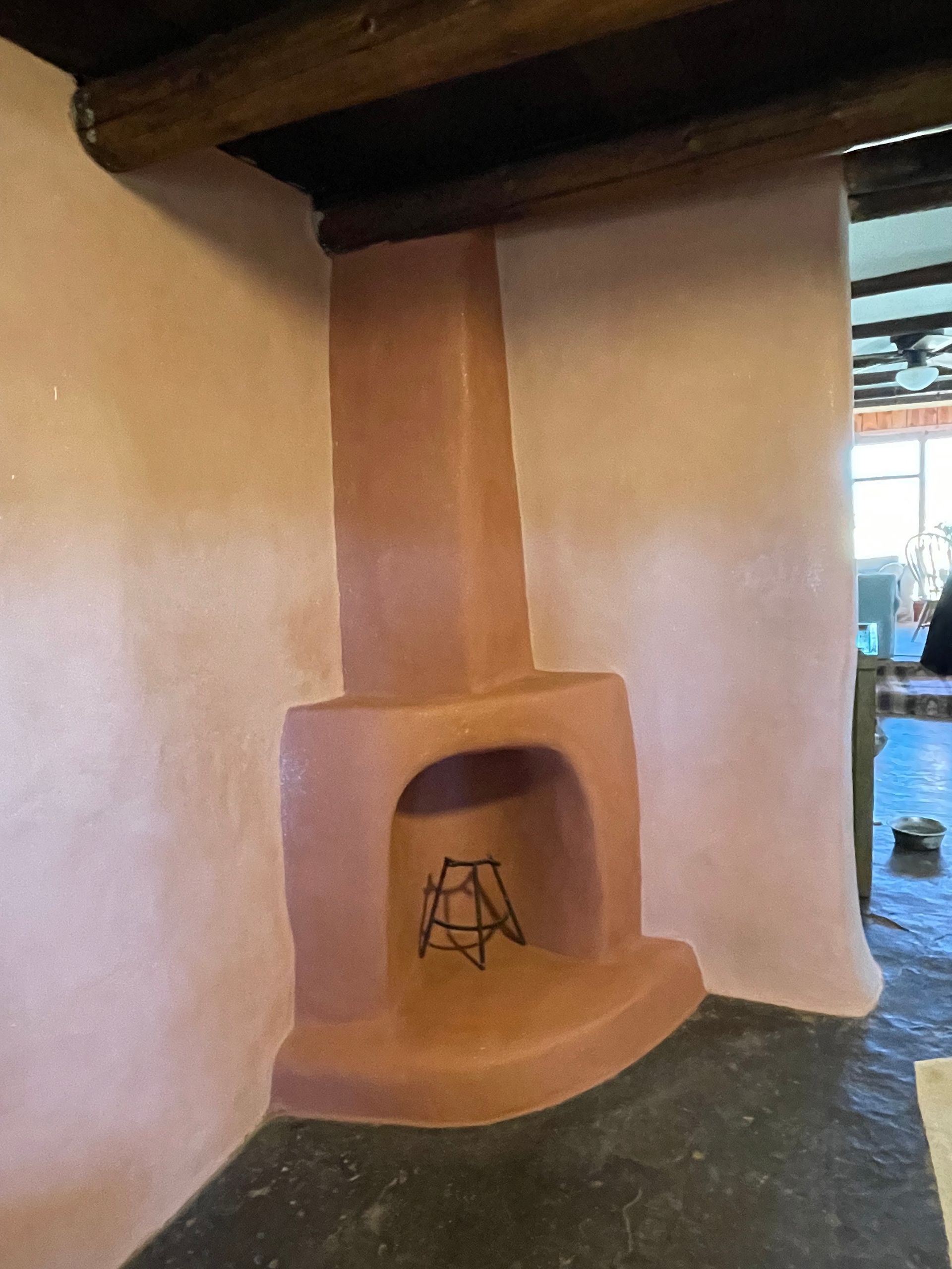 A beautifully refininshed adobe fireplace with new, smooth pink and salmon  colored plaster covering it.