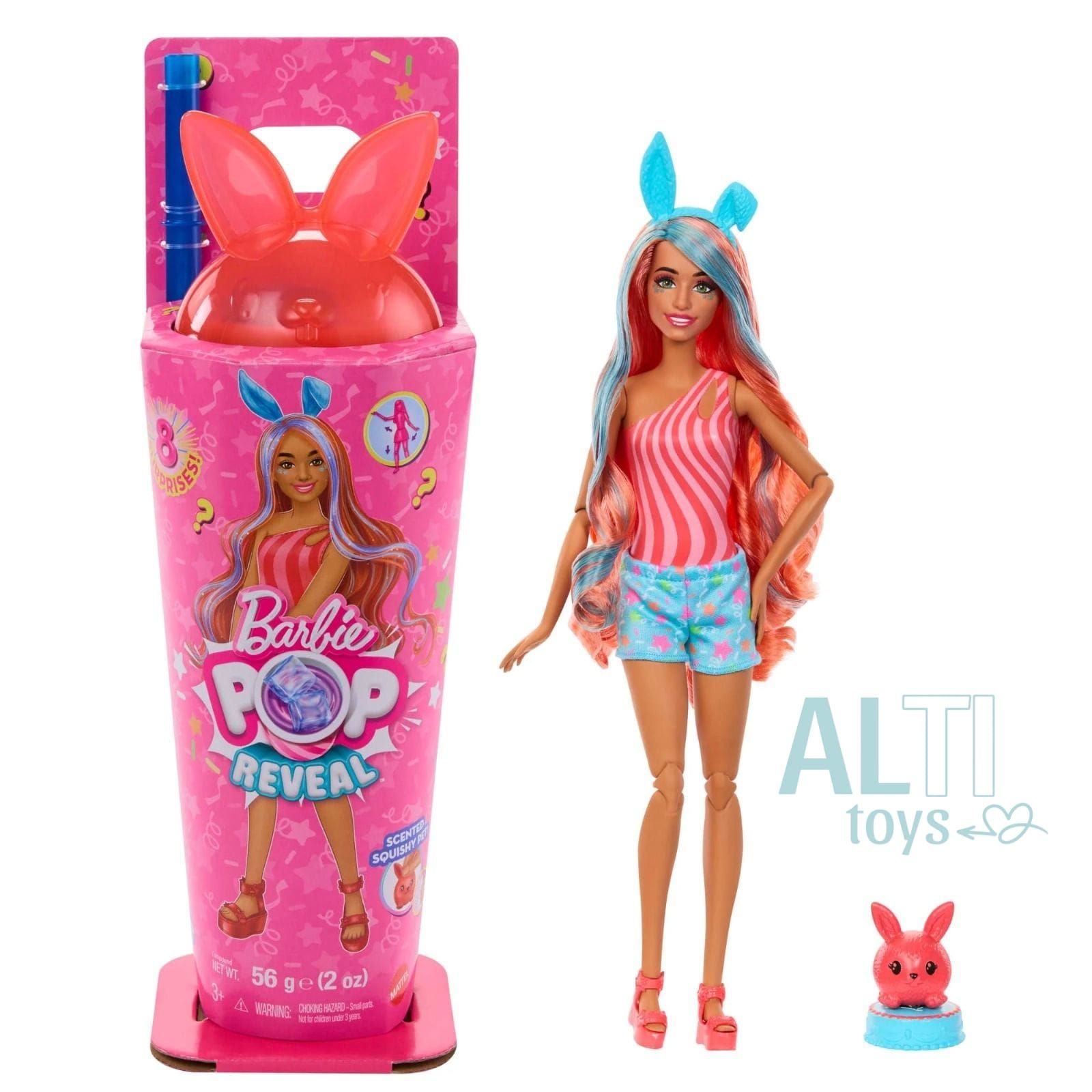 Una niña sonríe, sosteniendo slime rosa, con una muñeca Barbie y accesorios sobre una mesa. La muñeca tiene el pelo rosa y está junto a una taza temática.