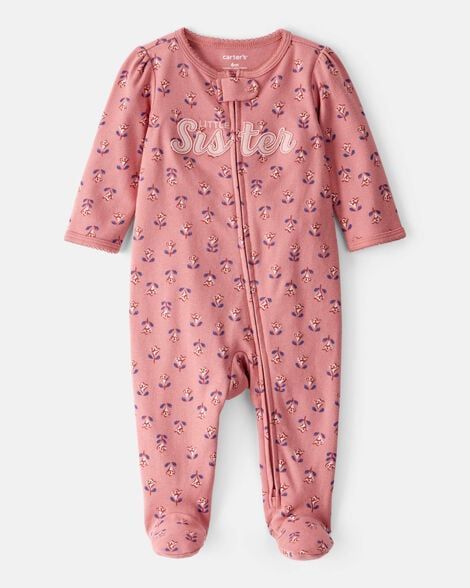 Pijama rosa con pies para bebé, estampado floral y bordado "hermana". Mangas largas y cremallera completa.