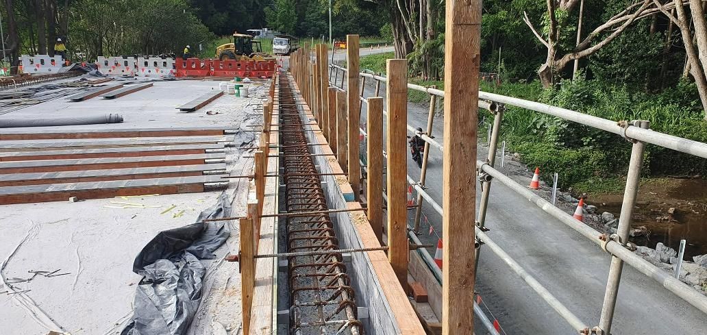 A Wooden Fence with Steels Is Being Built on The Side of A Road — Kontek Constructions in Jimboomba, QLD