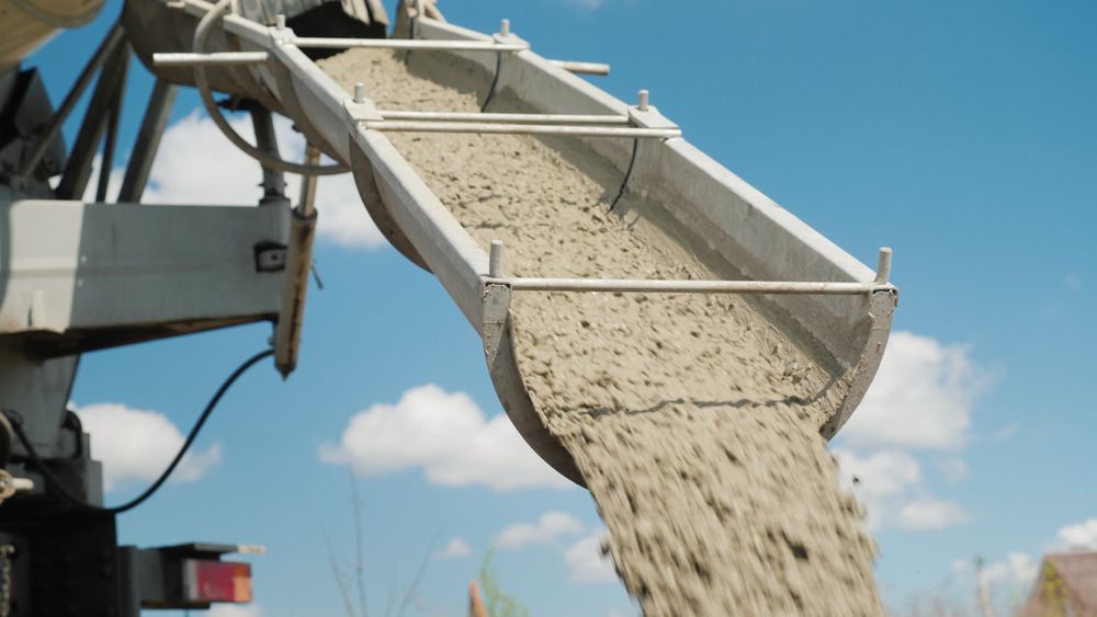 A Concrete Mixer is Pouring Concrete Into a Bucket — Kontek Constructions in Jimboomba, QLD