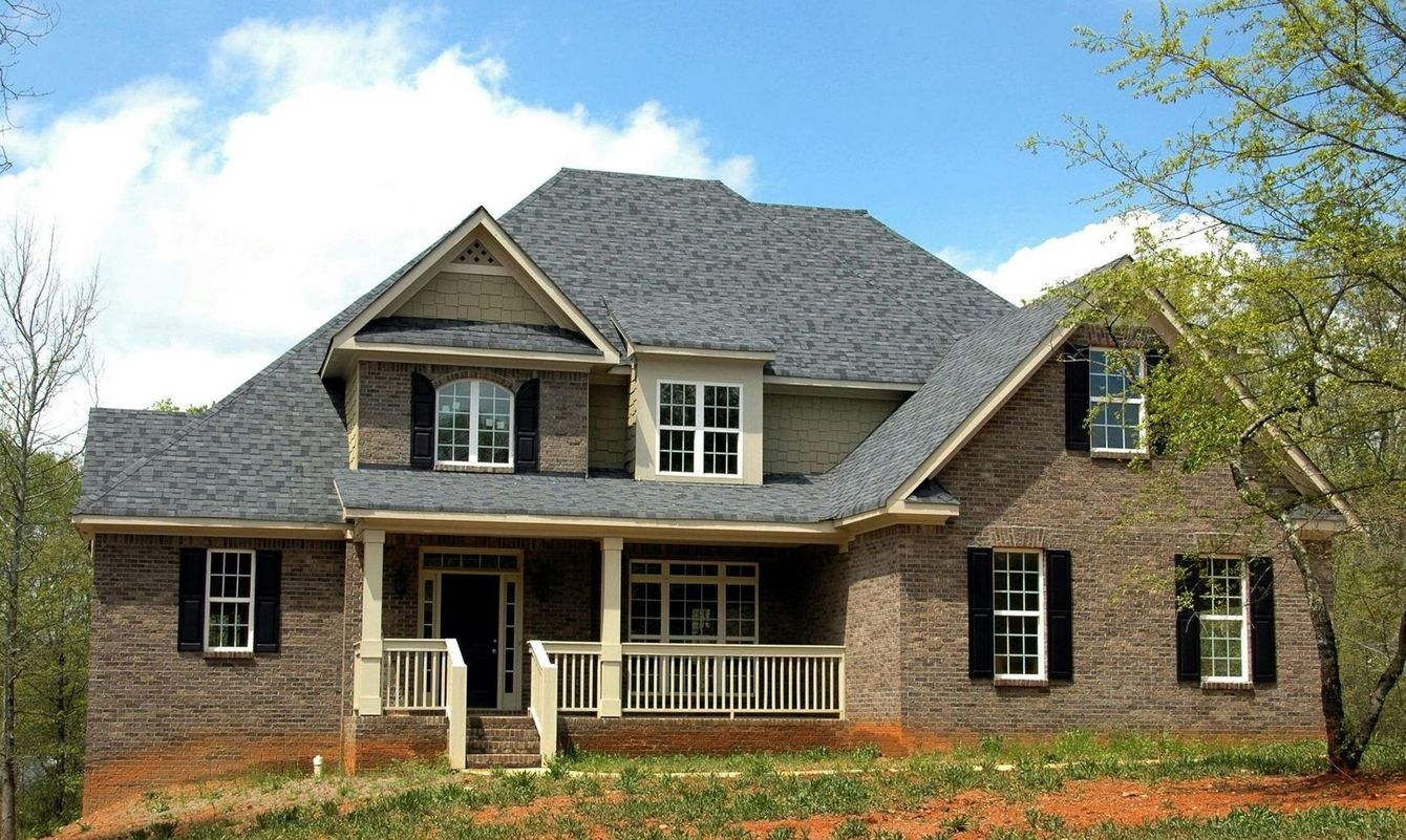 A large brick house with a gray roof and black shutters