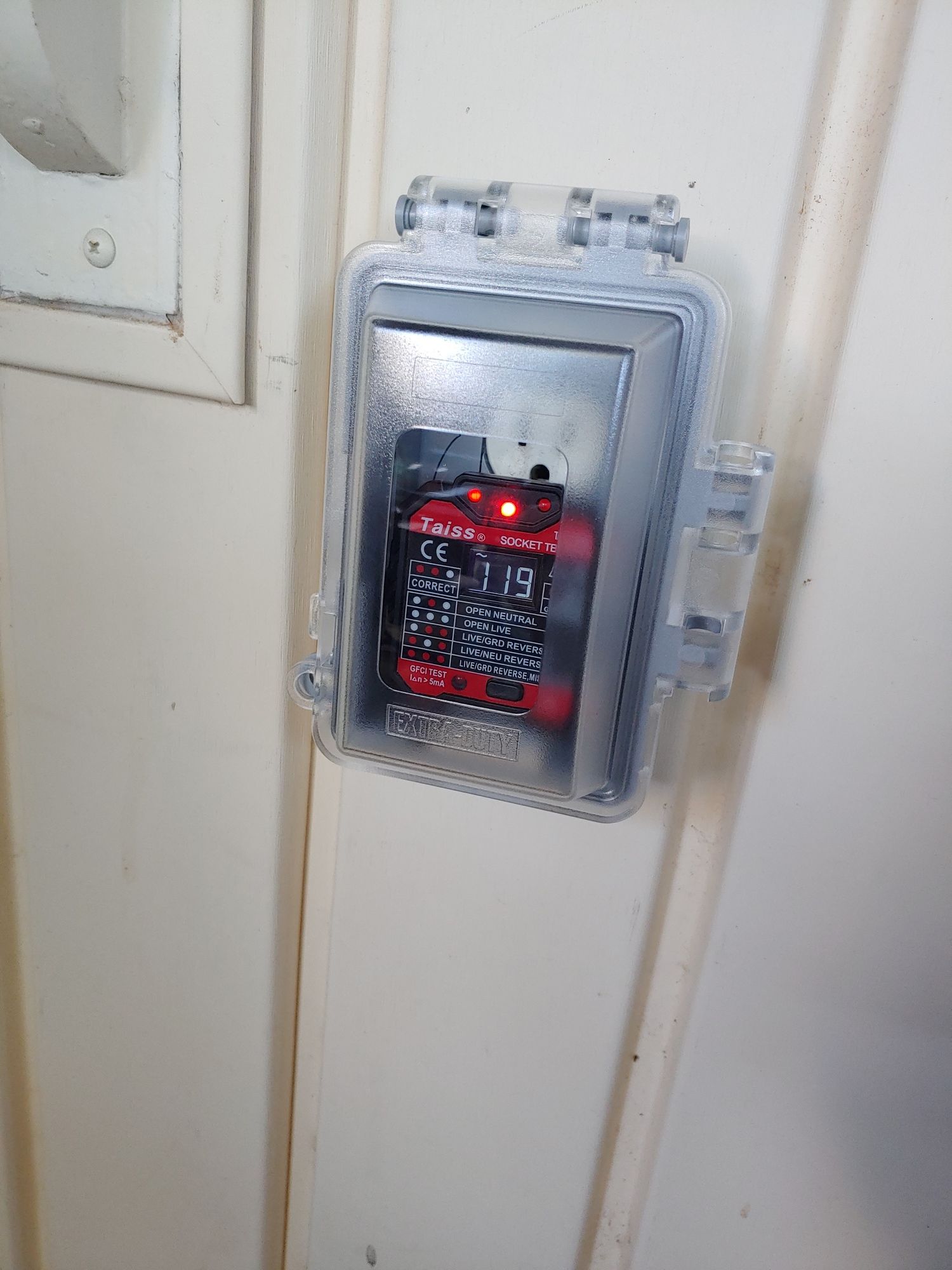 A box with a red light inside of it is sitting on a white wall.