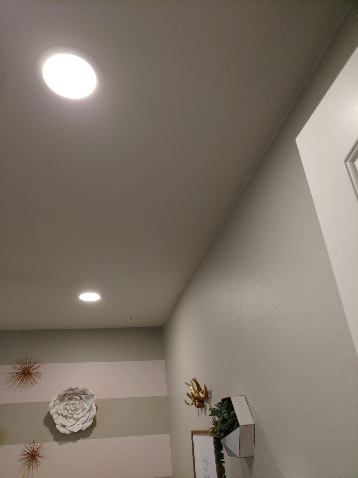 A bathroom with a light on the ceiling and a striped wall.