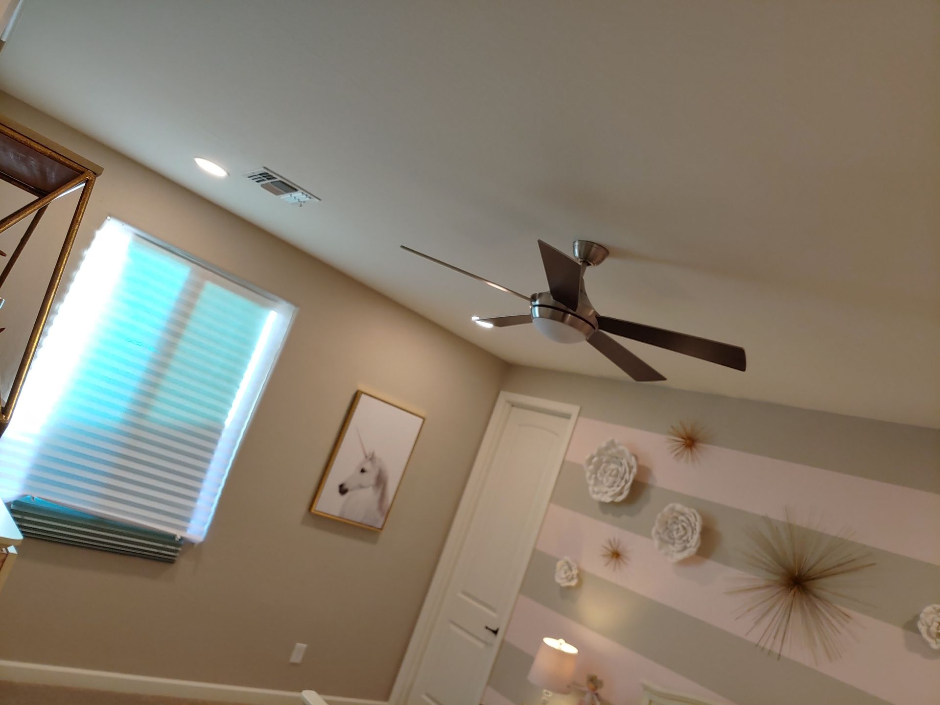 A bedroom with a ceiling fan and a picture on the wall