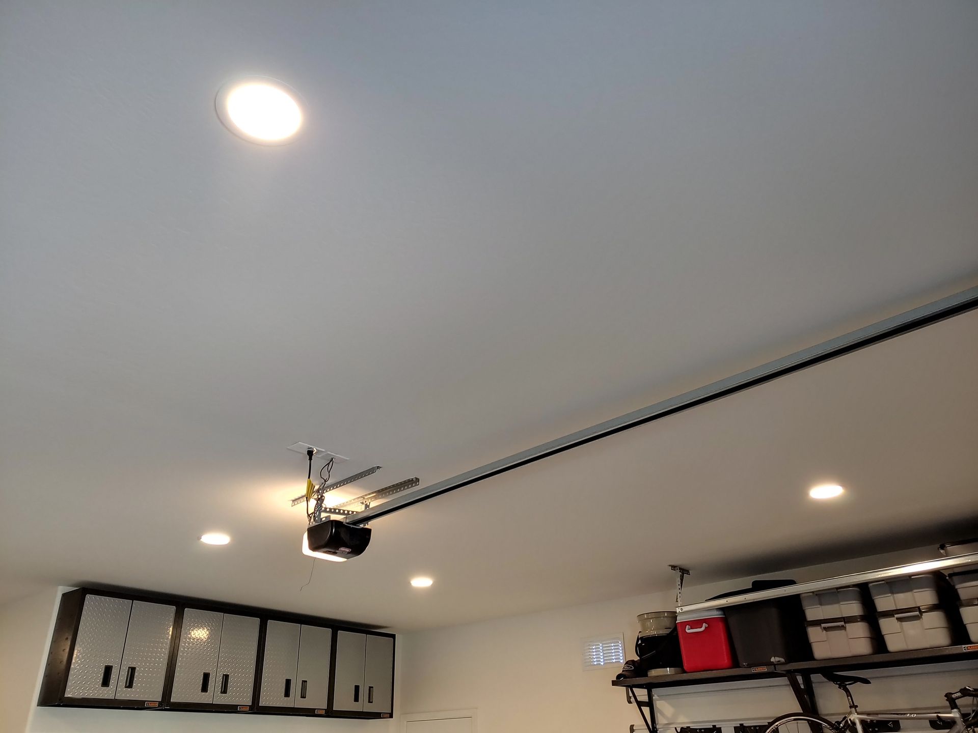 A garage door opener is hanging from the ceiling in a garage.