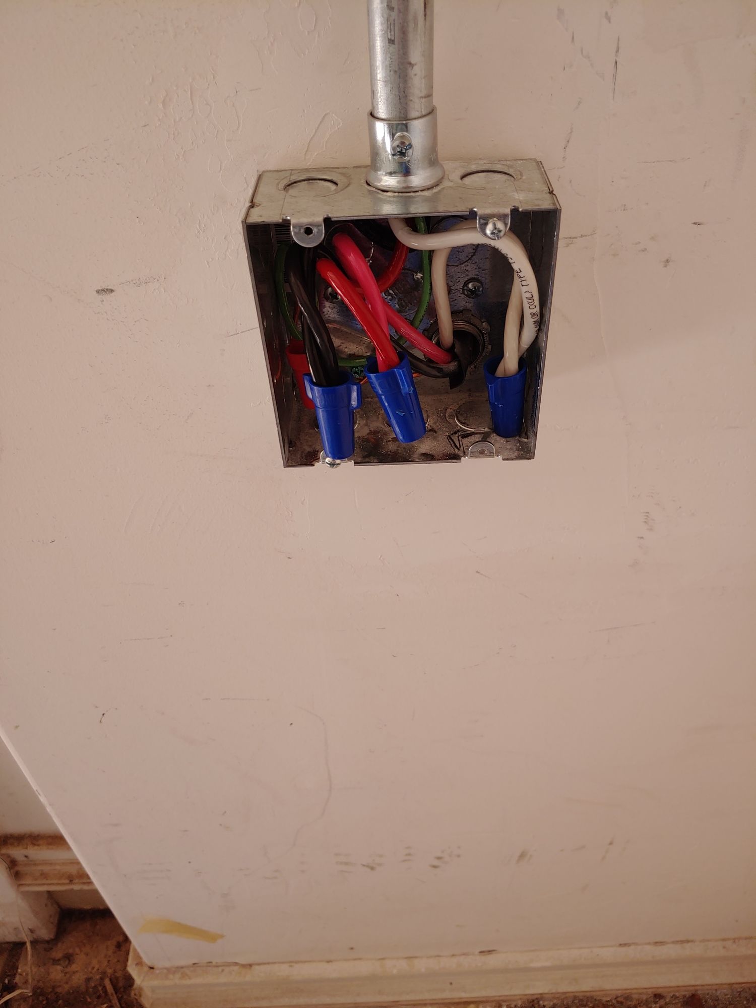 A box with wires in it is hanging on a wall.