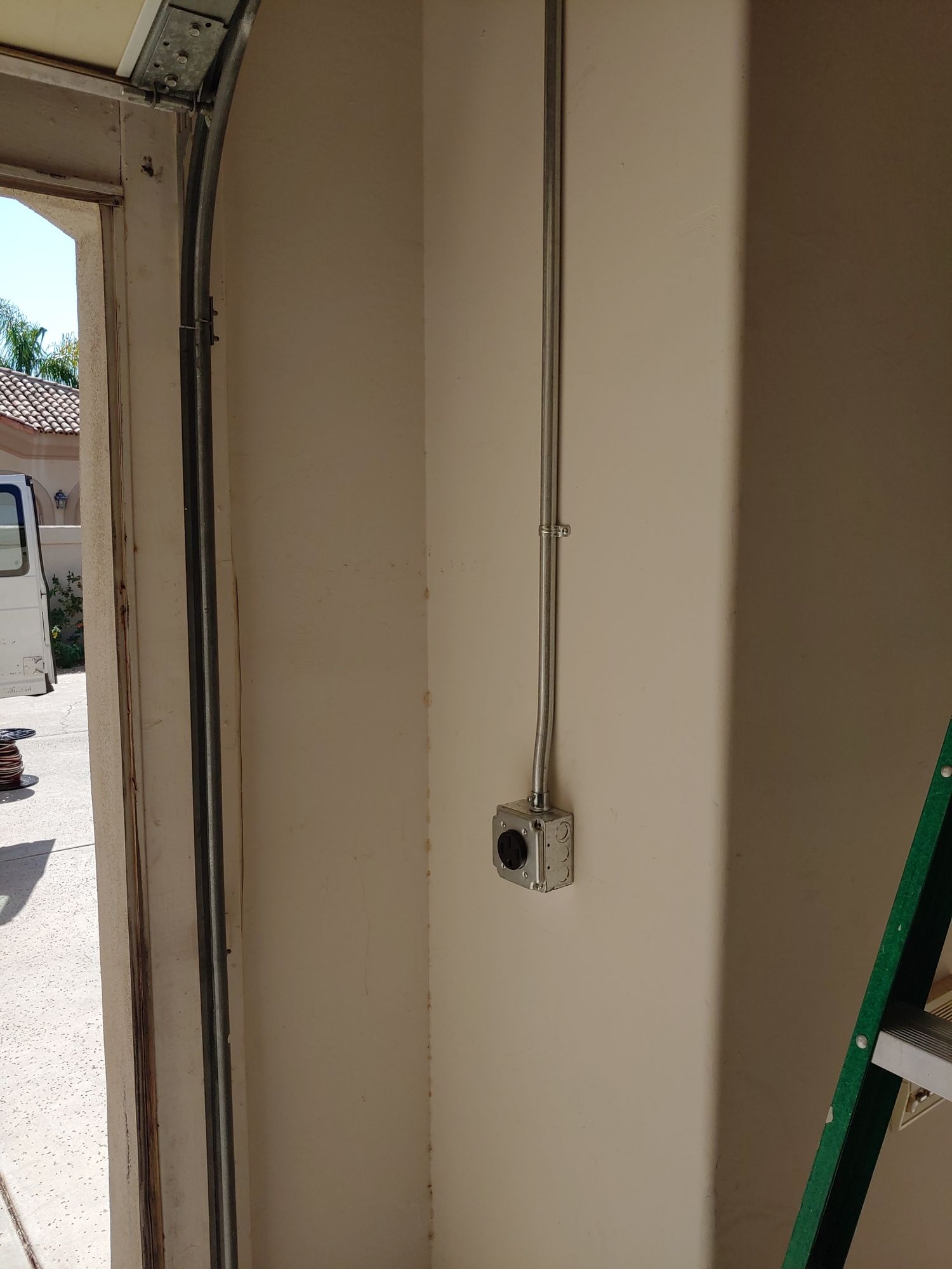 A green ladder is sitting next to a garage door.