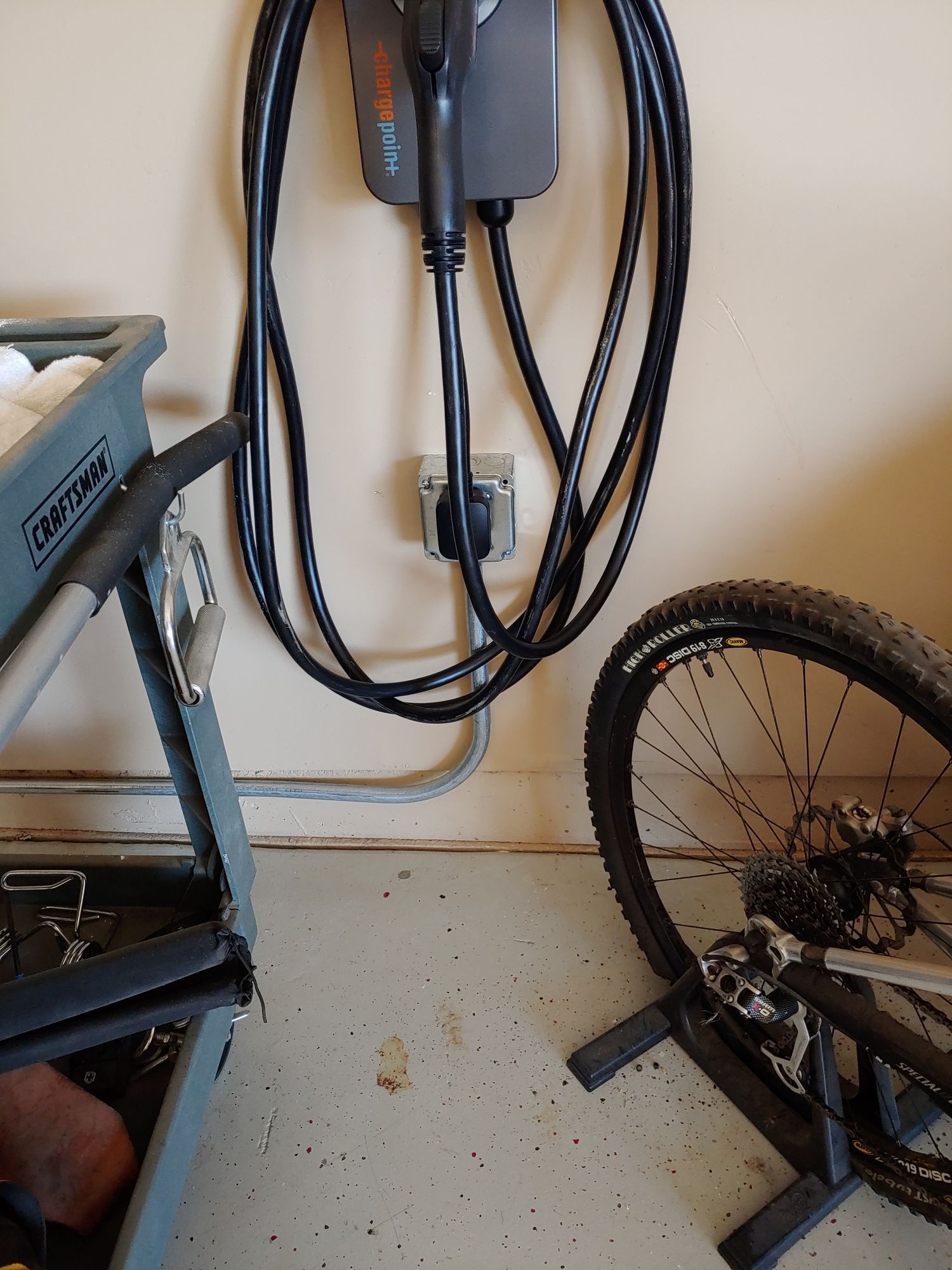 A bicycle is parked in front of a wall mounted charger