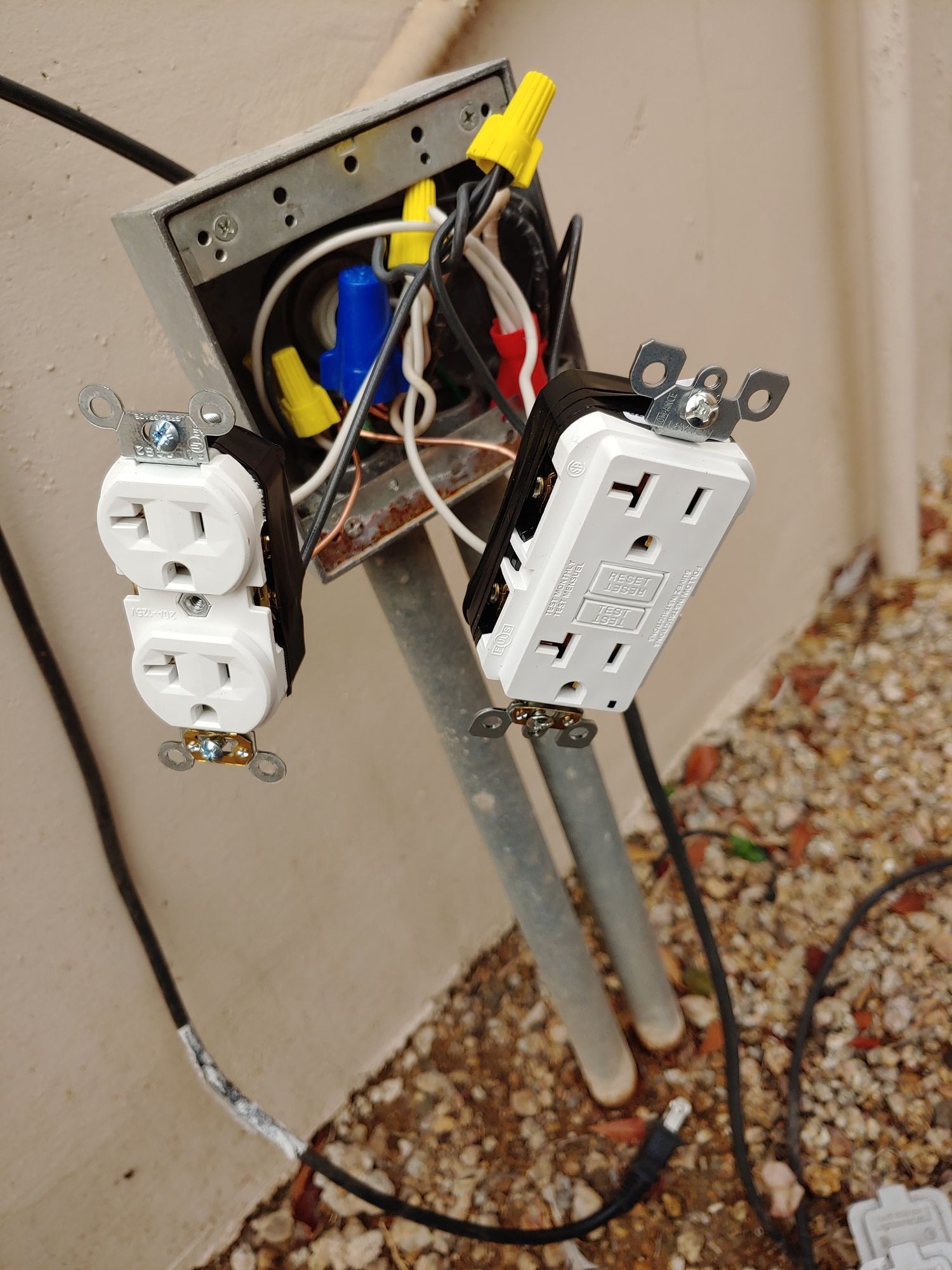 Two electrical outlets are connected to a metal pole.