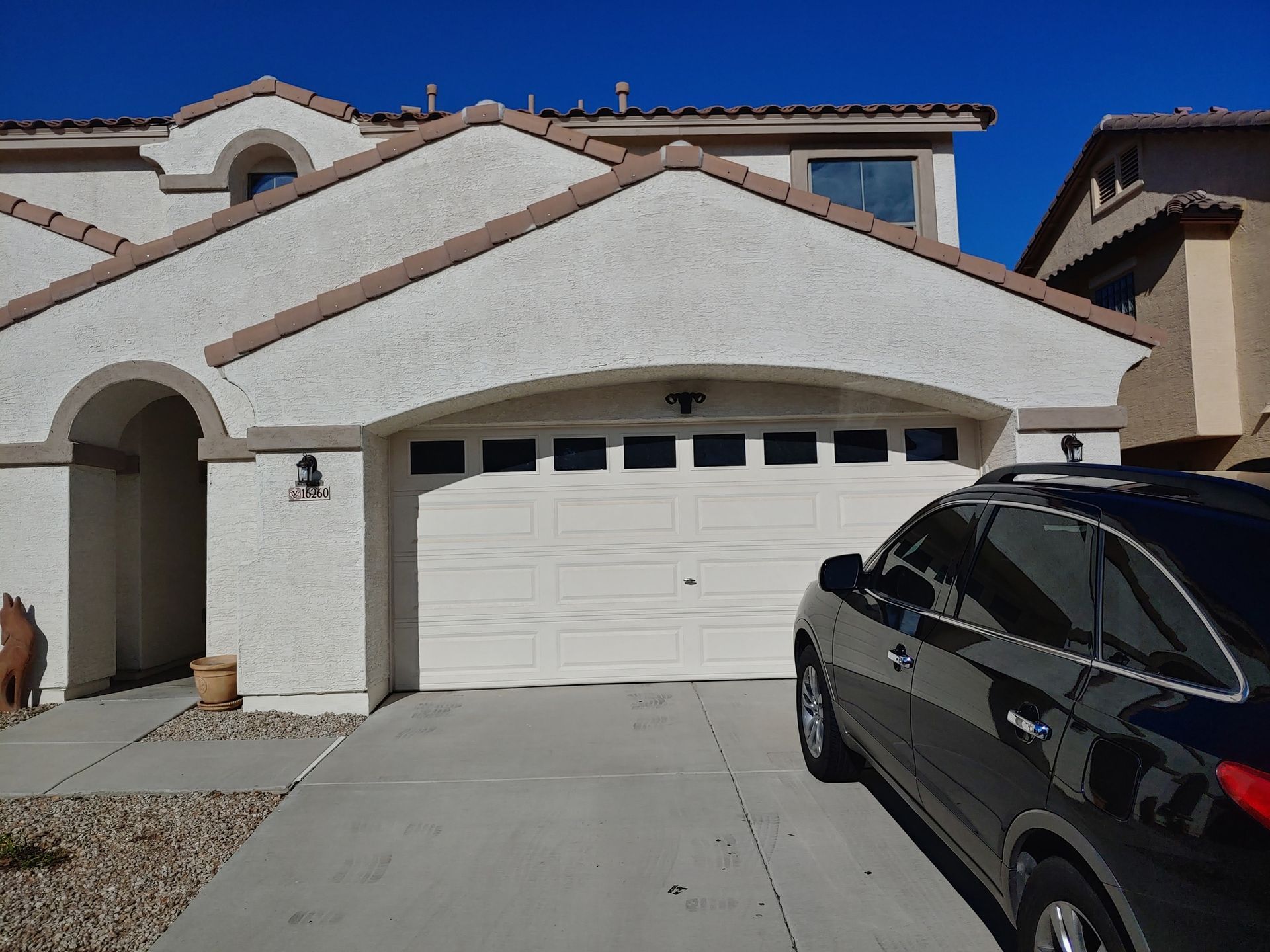 A black car is parked in front of a white house