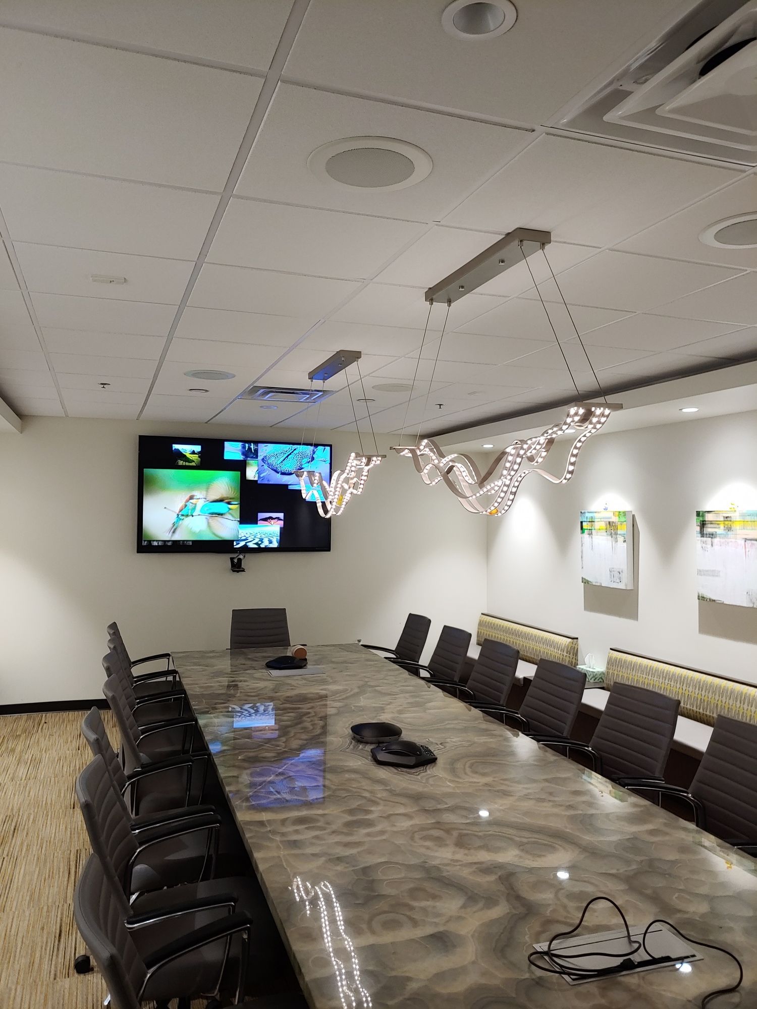 A conference room with a long table and chairs and a television on the wall.