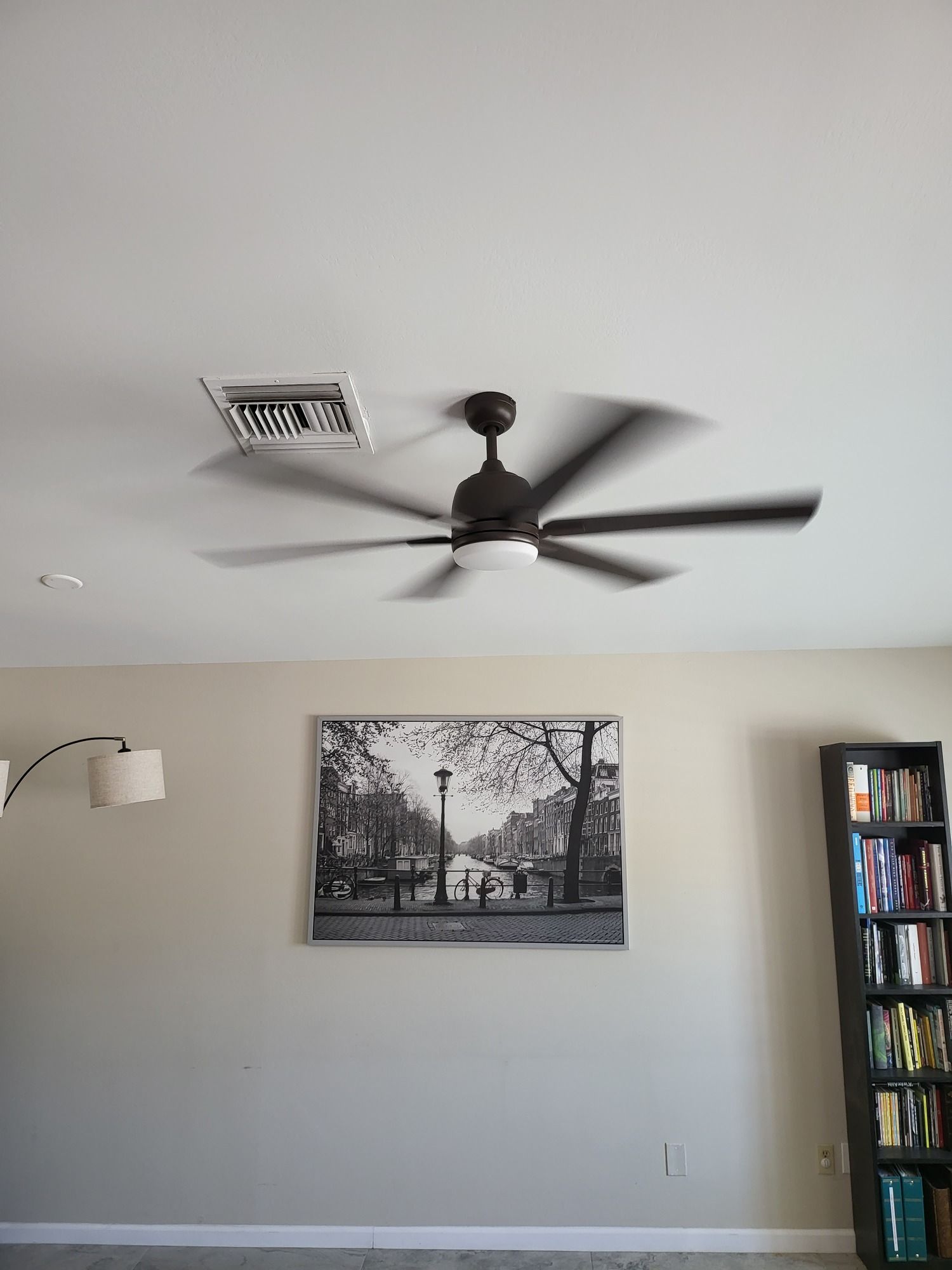 A living room with a ceiling fan and a picture on the wall.