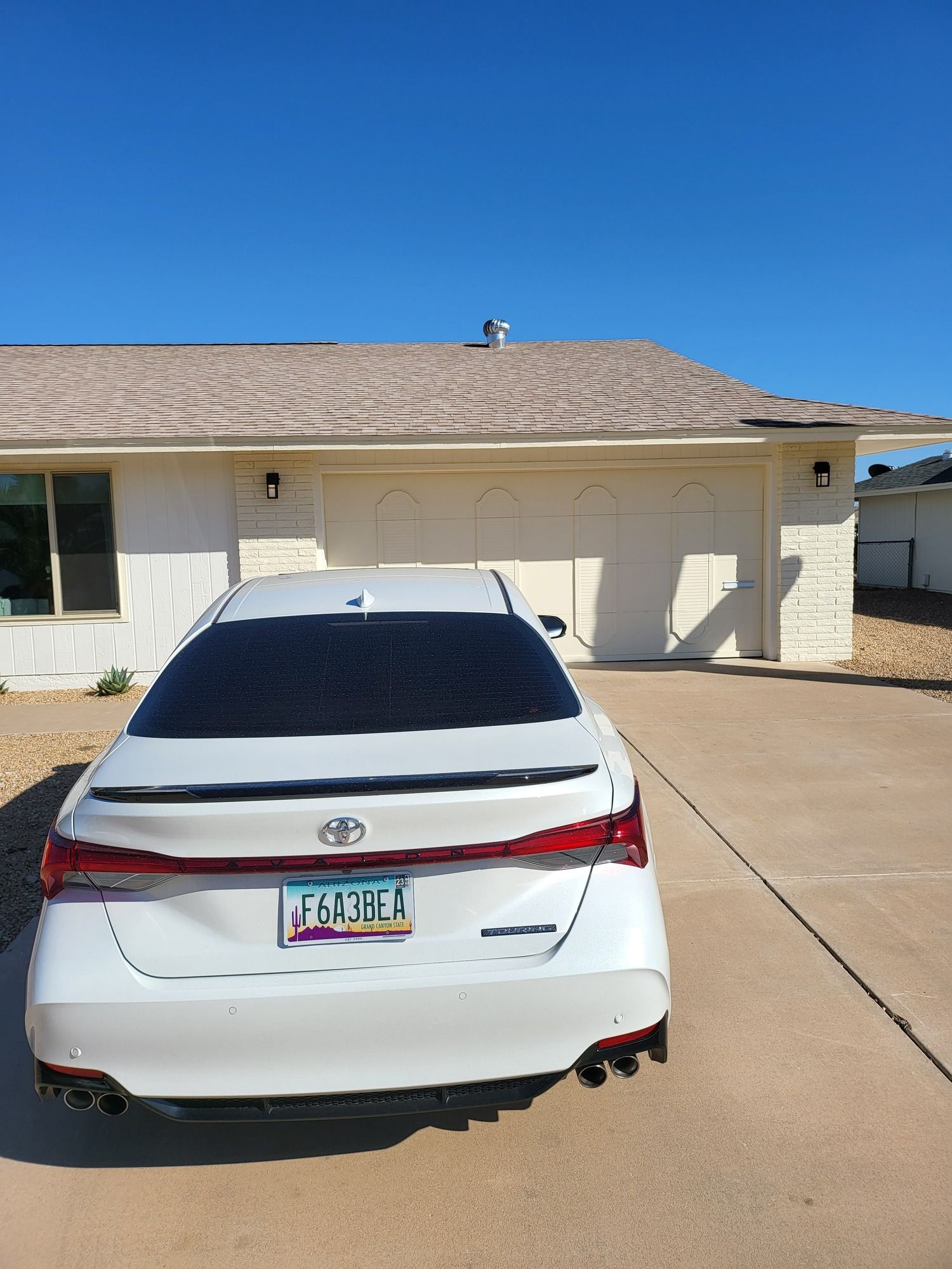 A white car is parked in front of a house.