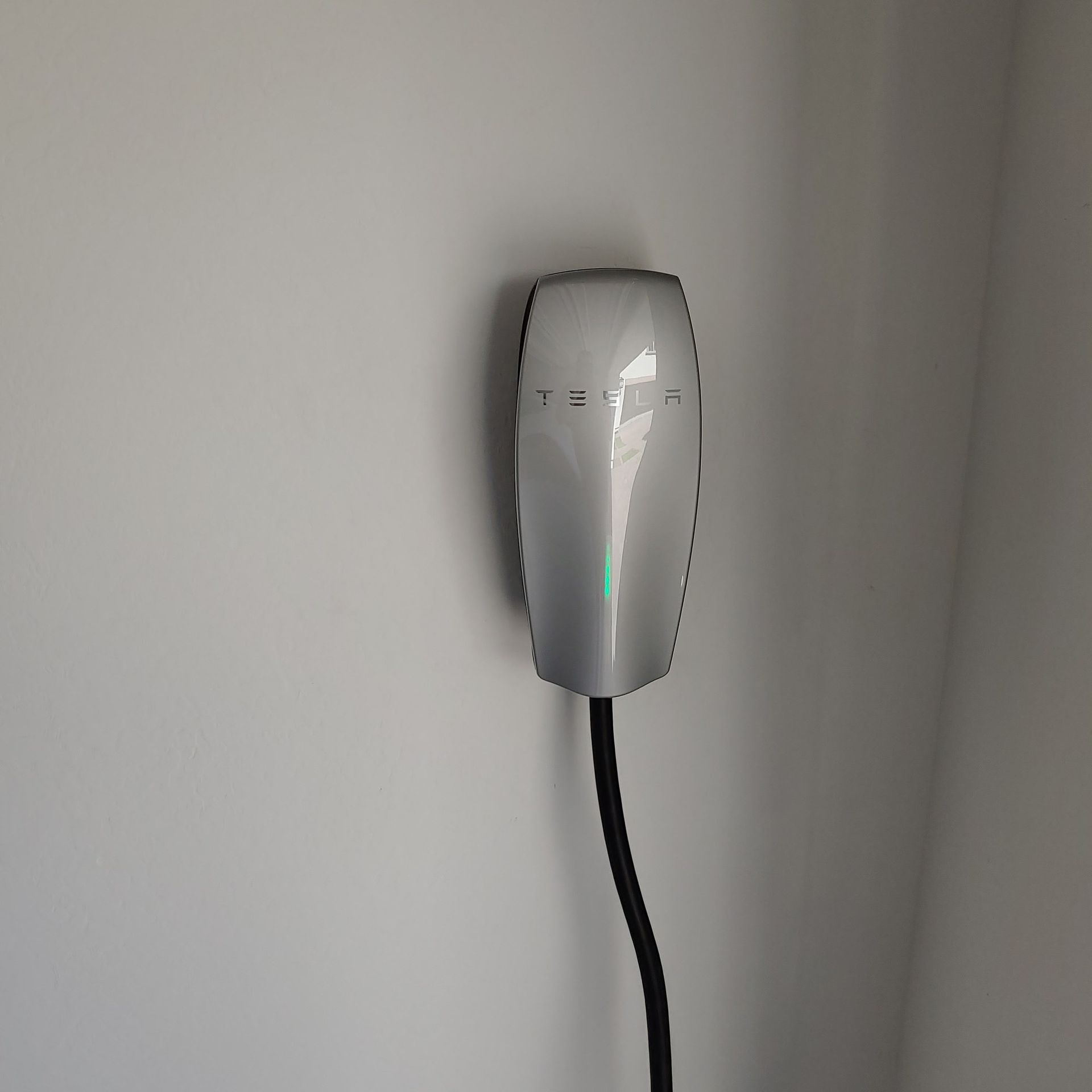 A tesla charging station is plugged into a wall