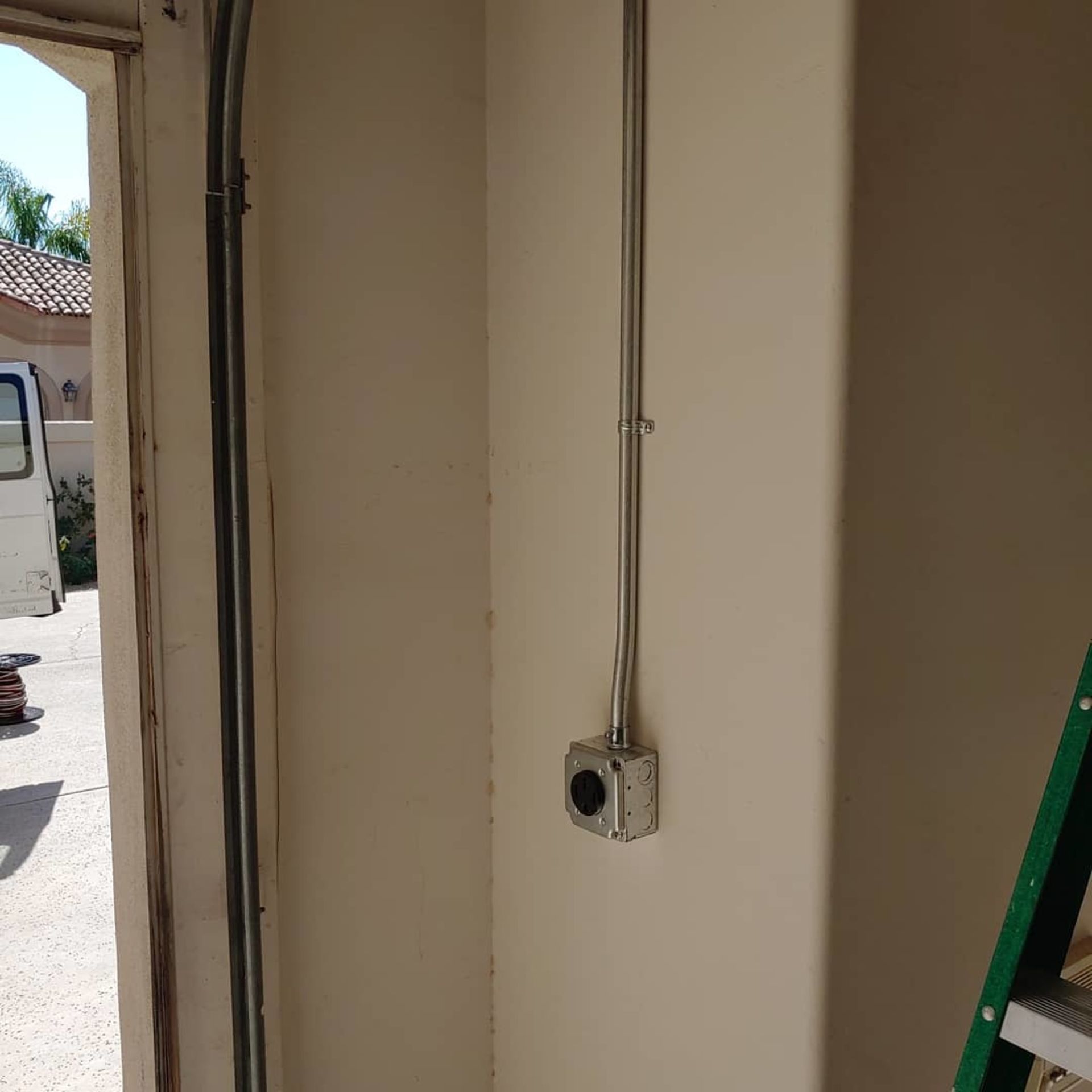 A ladder is sitting in a room next to a wall with a switch on it.