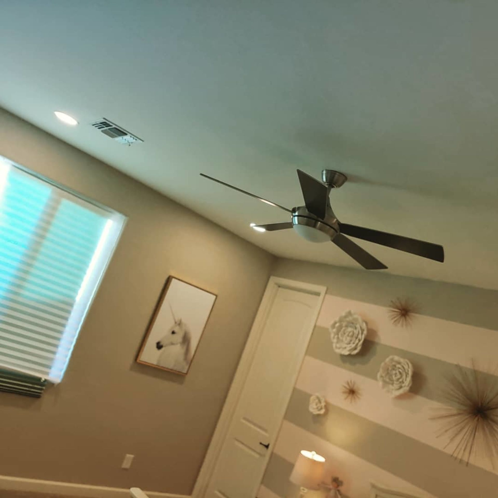 A bedroom with a ceiling fan and a picture of a horse on the wall