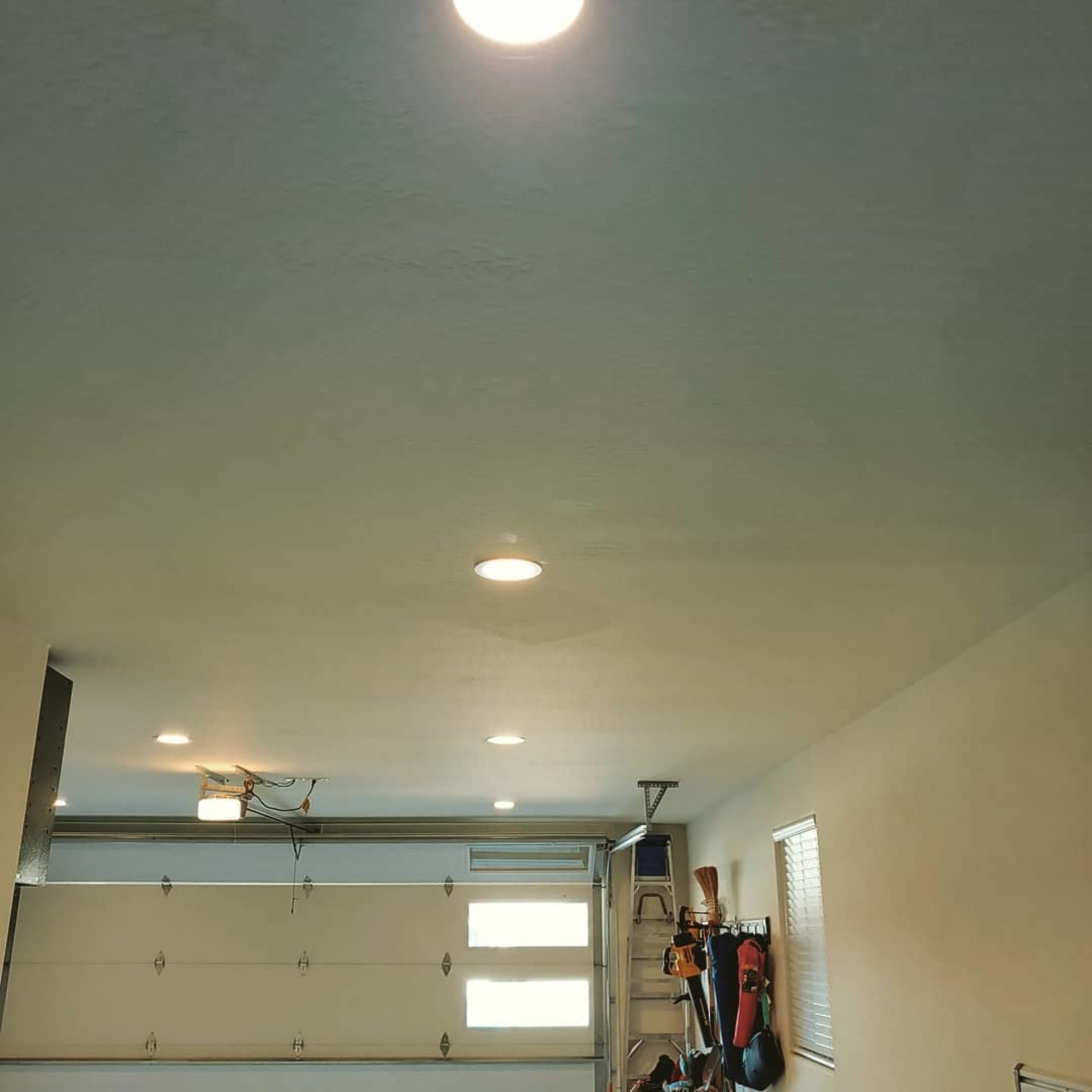 A garage with a garage door open and a light on the ceiling.