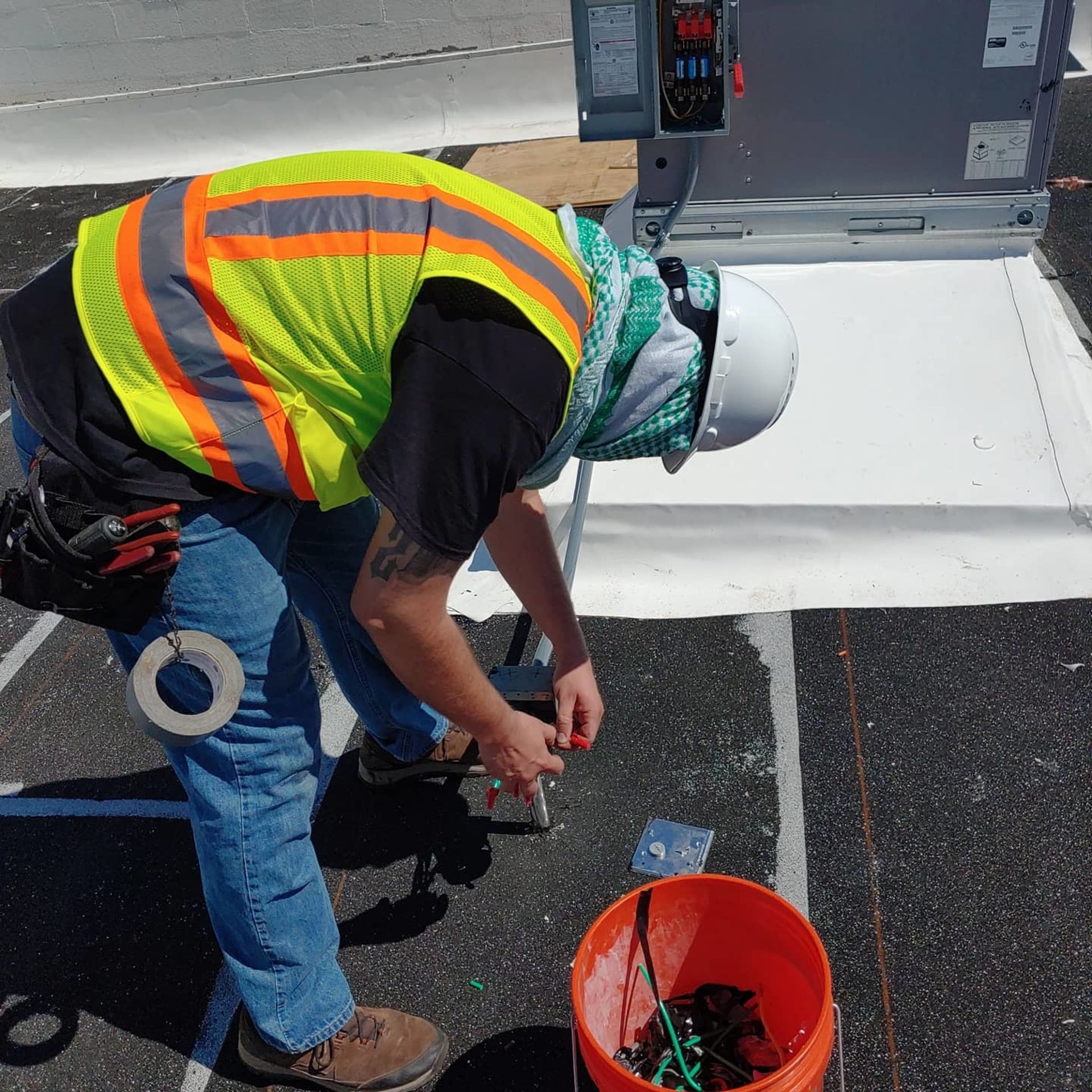 A man in a safety vest is working on a roof